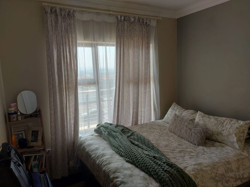 A cozy bedroom featuring a window with curtain rails and decorative coving, offering natural light and a view of the exterior.
