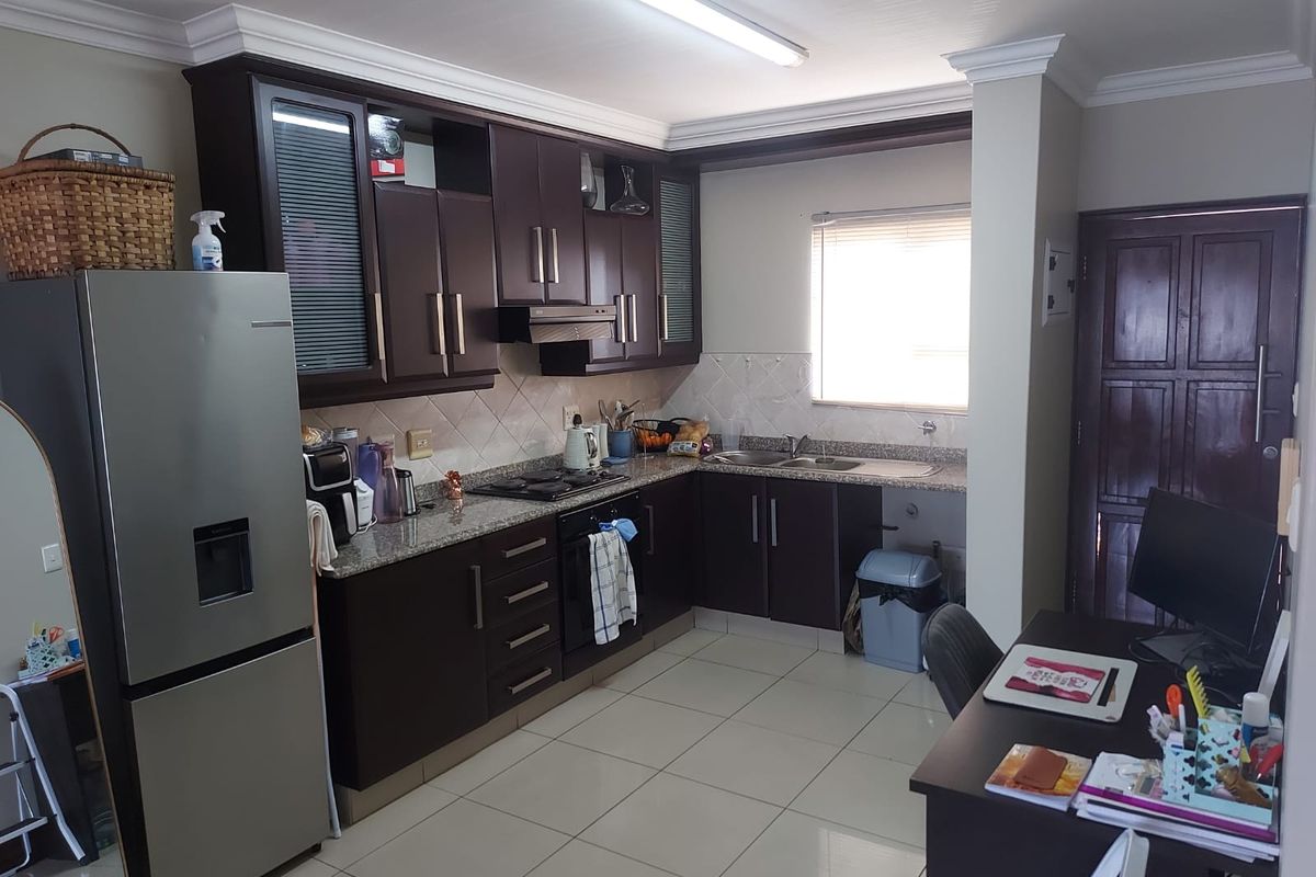 A functional kitchen featuring dark wood cabinetry, granite countertops, built-in oven, gas hob, and tiled flooring, offering a practical layout for daily cooking.
