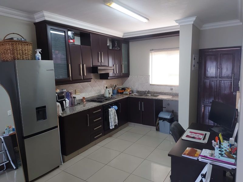 A functional kitchen featuring dark wood cabinetry, granite countertops, built-in oven, gas hob, and tiled flooring, offering a practical layout for daily cooking.