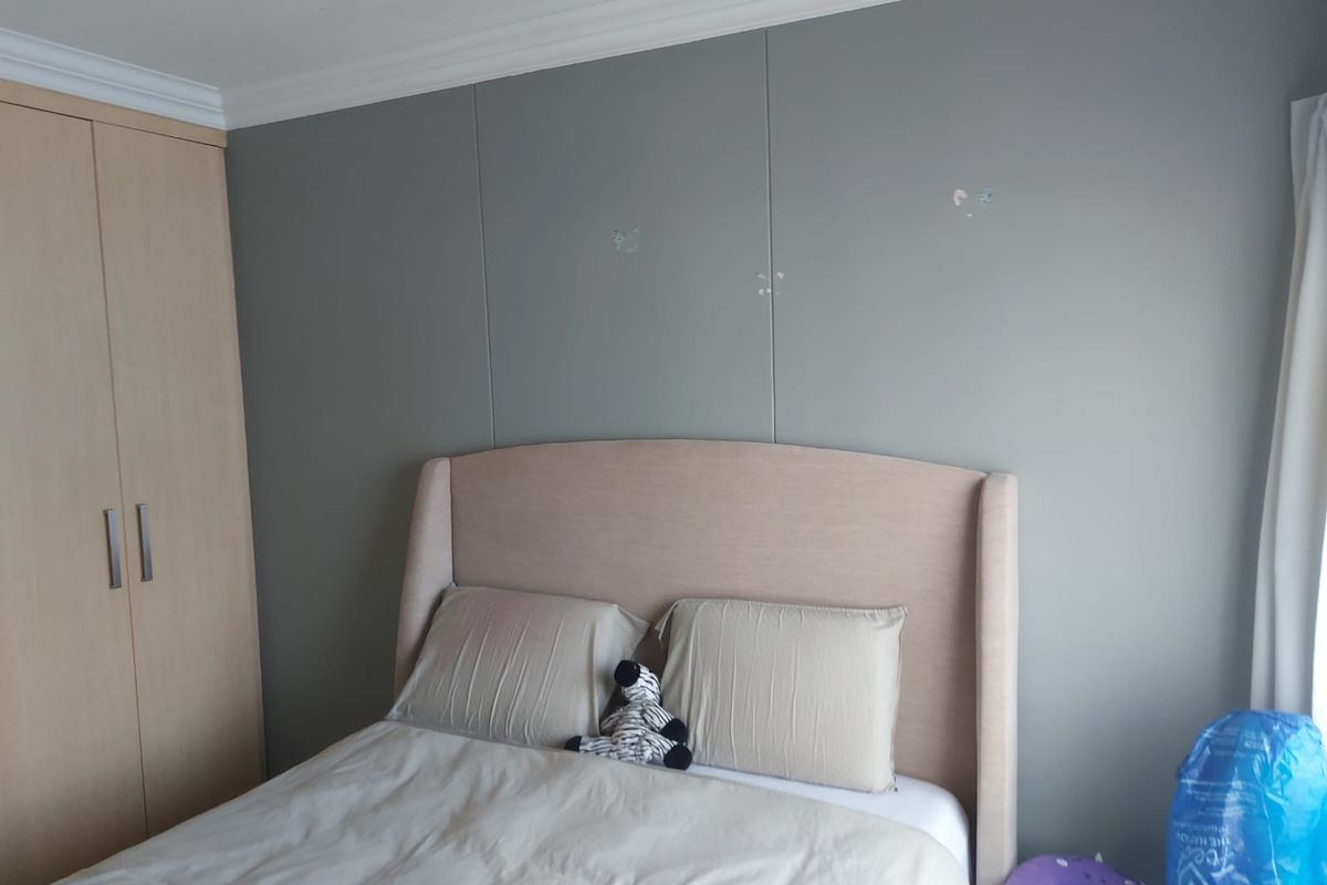A bedroom featuring a built-in wardrobe and crown molding, with neutral wall tones and a standard layout.