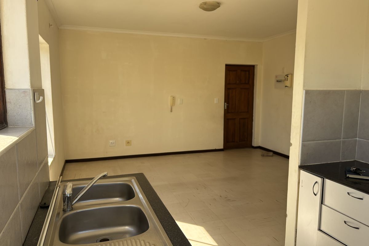 An empty kitchen area featuring a double bowl sink, tiled splashbacks, and built-in cabinetry, offering a blank canvas for renovation.