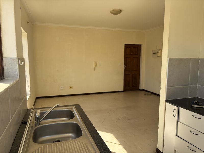 An empty kitchen area featuring a double bowl sink, tiled splashbacks, and built-in cabinetry, offering a blank canvas for renovation.