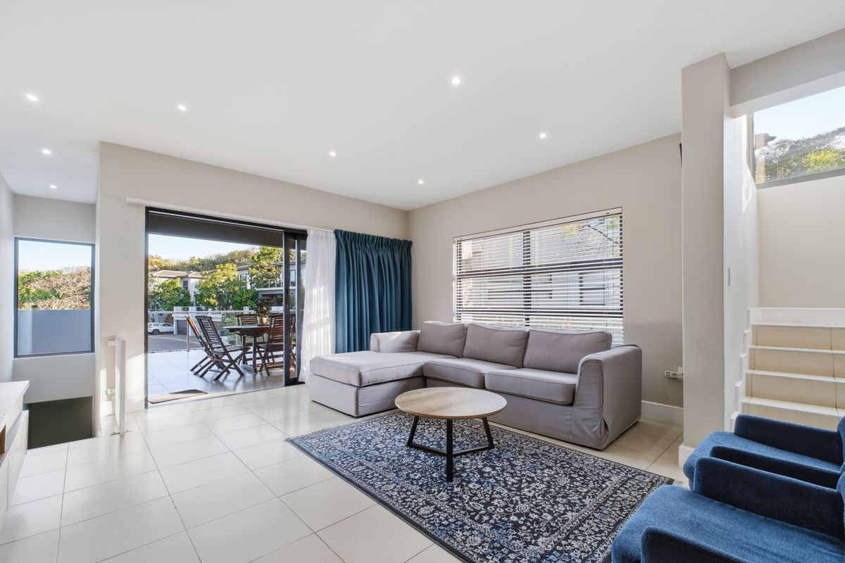 Bright and spacious living area featuring tiled floors, recessed lighting, and large sliding glass doors providing seamless access to the outdoor patio.