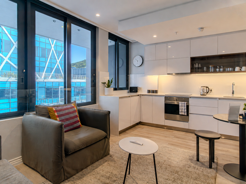 Modern open-plan apartment featuring a sleek kitchen with integrated appliances and floor-to-ceiling windows providing ample natural light.