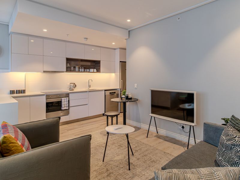 Modern open-plan living area featuring a sleek, well-equipped kitchen with integrated appliances and contemporary finishes throughout.