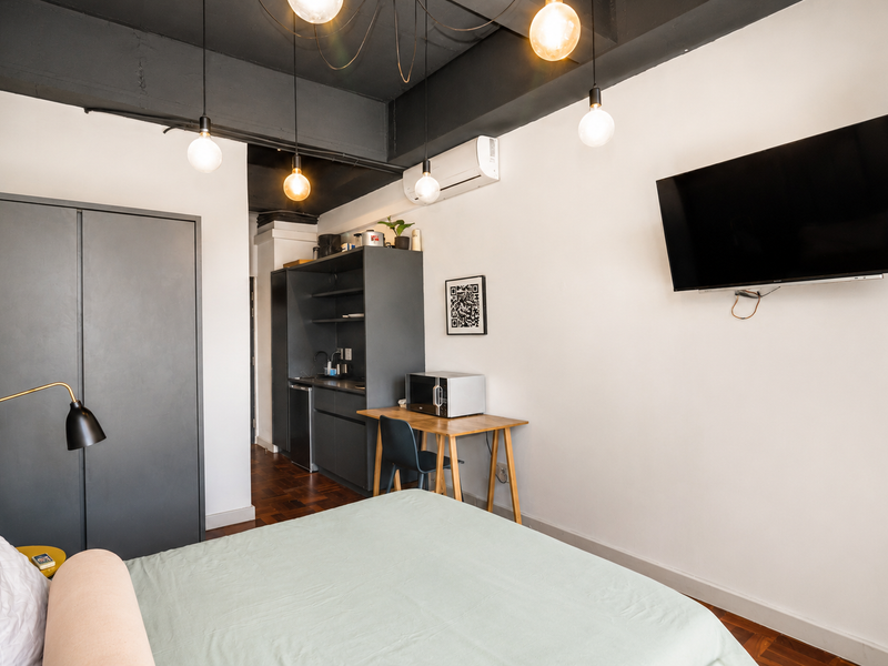 Modern studio bedroom featuring parquet flooring, a built-in wardrobe, split-system air conditioning, and a compact kitchenette area with sink and cabinetry.