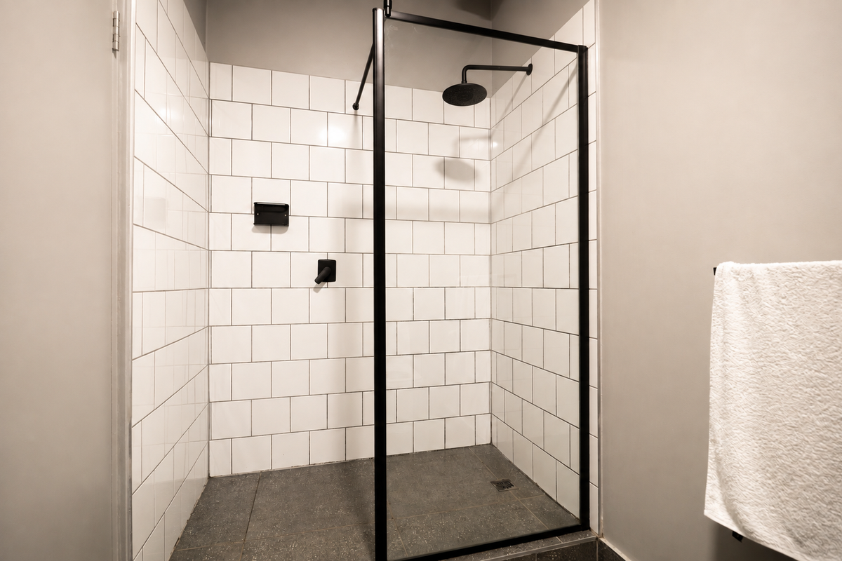 Modern walk-in shower featuring white subway wall tiles, a black metal frame, and a contemporary rain shower head.