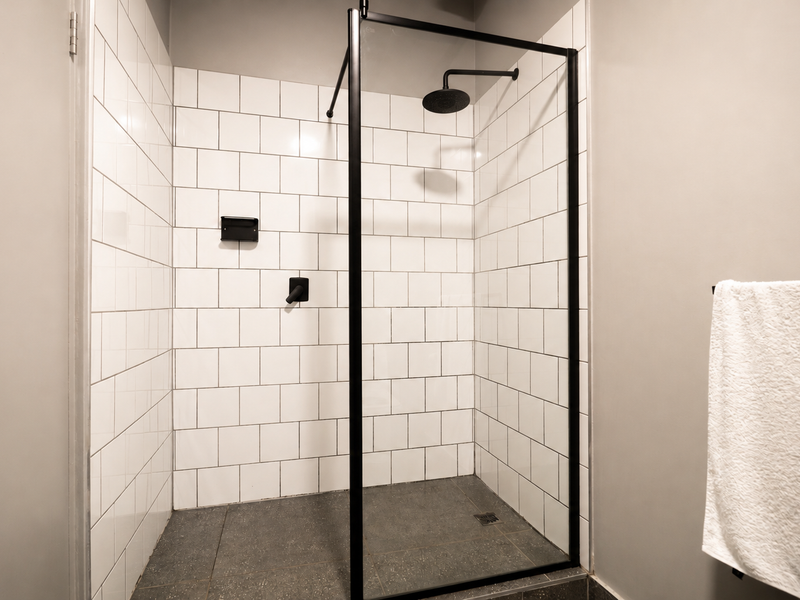 Modern walk-in shower featuring white subway wall tiles, a black metal frame, and a contemporary rain shower head.