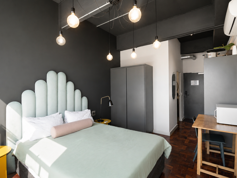 Modern bedroom featuring dark accent walls, parquet flooring, exposed ceiling, built-in wardrobe, and air conditioning unit.