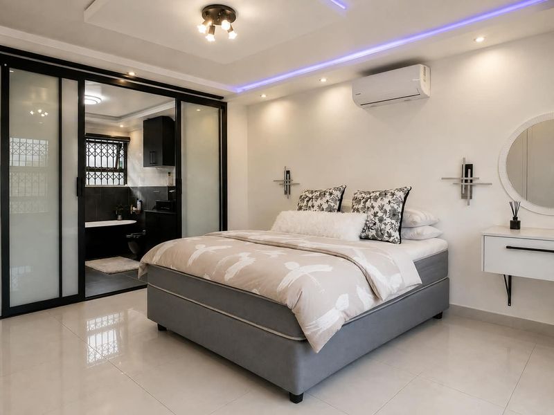Modern bedroom featuring tiled floors, recessed ceiling lighting with LED accents, split-system air conditioning, and a sleek sliding glass door leading to an en-suite bathroom.