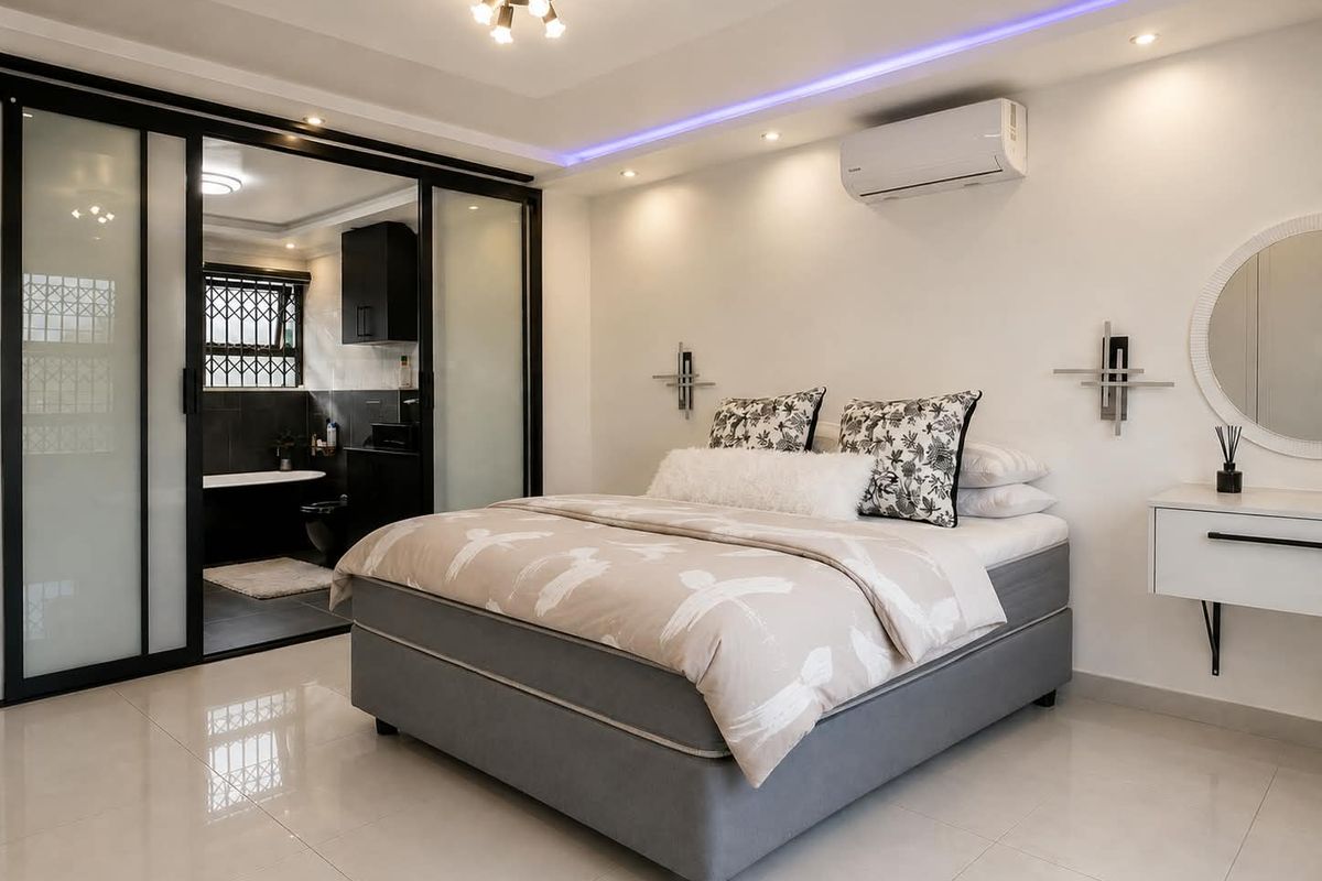 Modern bedroom featuring tiled floors, recessed ceiling lighting with LED accents, split-system air conditioning, and a sleek sliding glass door leading to an en-suite bathroom.