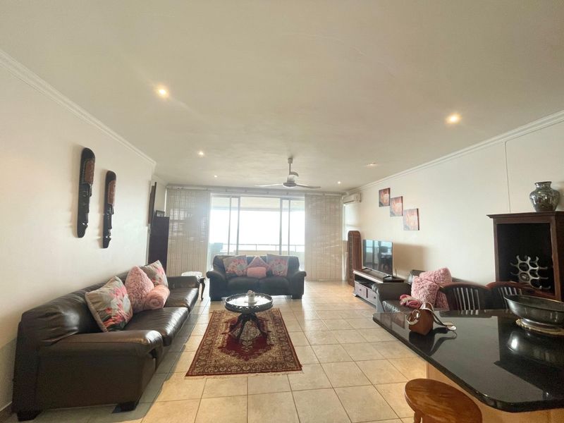 Spacious open-plan living area featuring ceramic floor tiles, recessed lighting, a ceiling fan, and large sliding doors leading to a balcony.