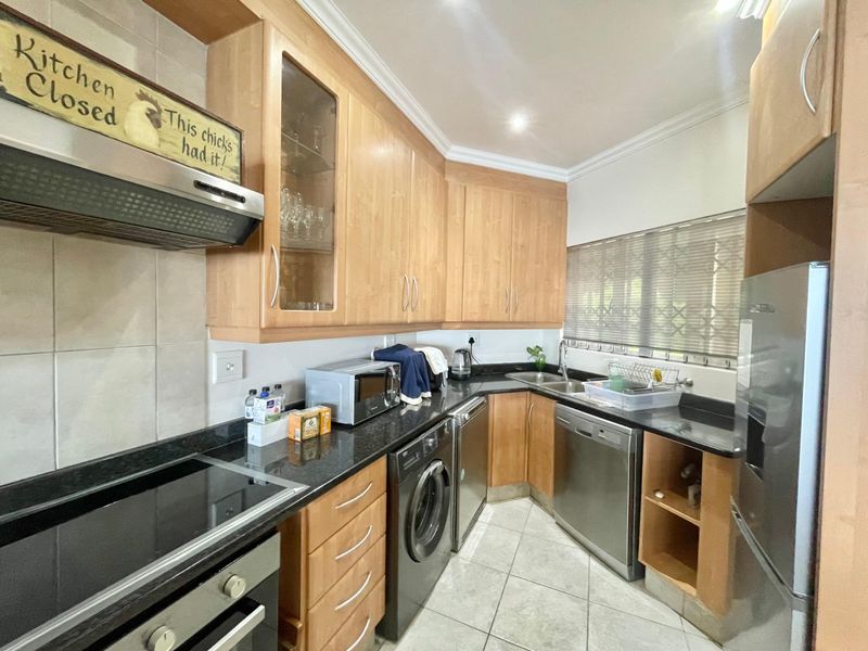 A functional kitchen featuring light wood cabinetry, granite countertops, integrated appliances, and tiled flooring, offering a practical layout for daily meal preparation.