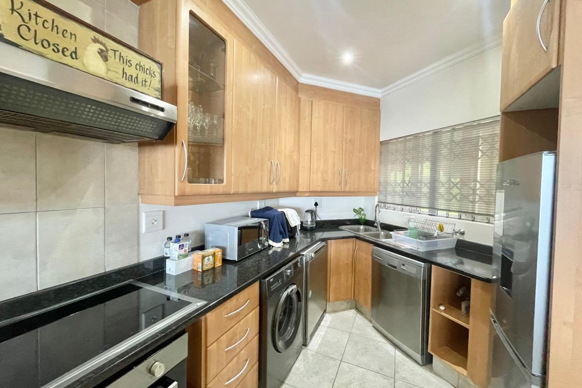A functional kitchen featuring light wood cabinetry, granite countertops, integrated appliances, and tiled flooring, offering a practical layout for daily meal preparation.