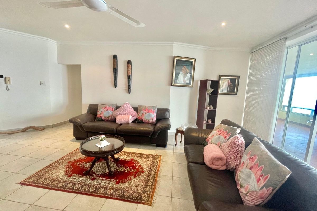 Spacious living room featuring neutral tiled flooring, a ceiling fan, and large sliding glass doors providing access to the outdoor area.