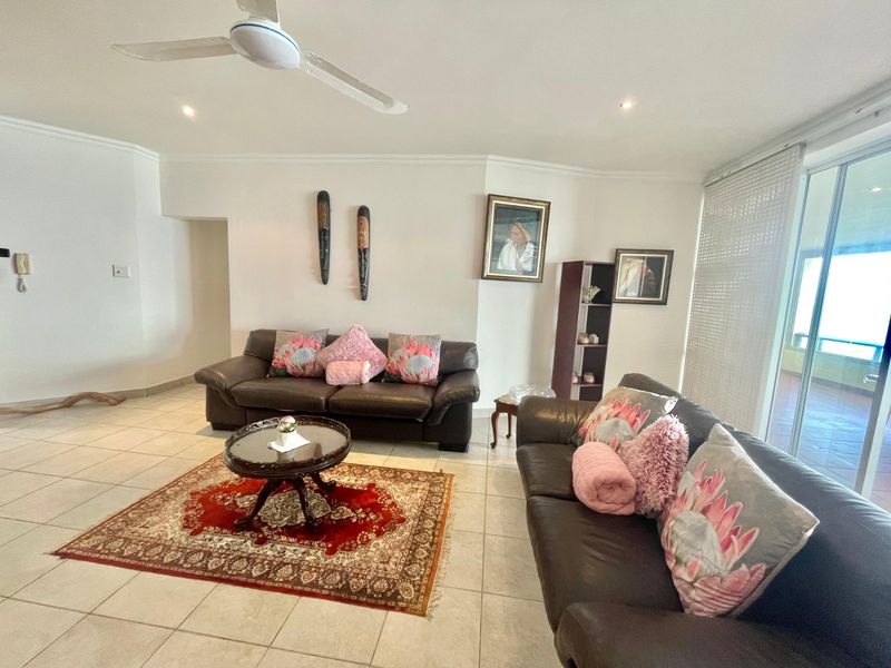 Spacious living room featuring neutral tiled flooring, a ceiling fan, and large sliding glass doors providing access to the outdoor area.