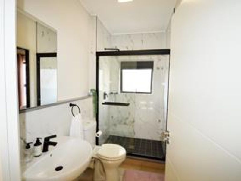 Modern bathroom featuring a walk-in shower with a glass enclosure, marble-look wall tiles, a contemporary basin, and sleek black fixtures.