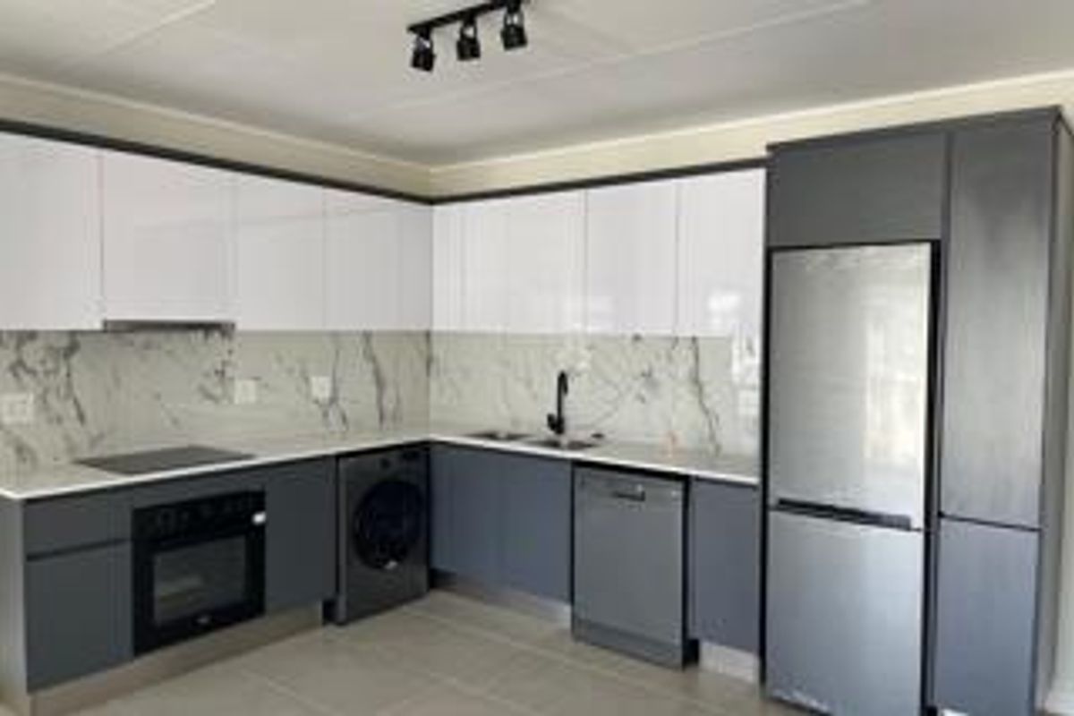 Modern kitchen featuring sleek two-tone cabinetry, marble-effect splashback, built-in oven, hob, and integrated fixtures in a clean, contemporary layout.