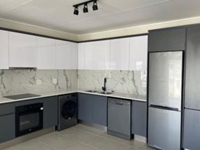 Modern kitchen featuring sleek two-tone cabinetry, marble-effect splashback, built-in oven, hob, and integrated fixtures in a clean, contemporary layout.