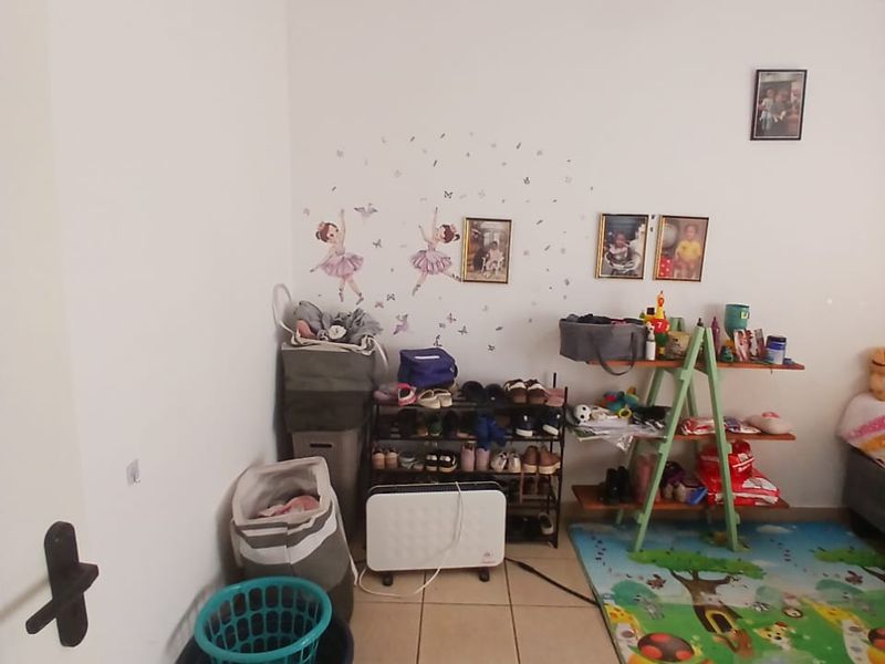 A bedroom featuring tiled flooring and a ceiling fan, currently utilized as a multi-purpose storage and play area.