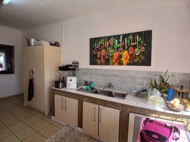 A functional kitchen area featuring built-in cabinetry, a subway tile backsplash, and a stainless steel double sink with tiled flooring.