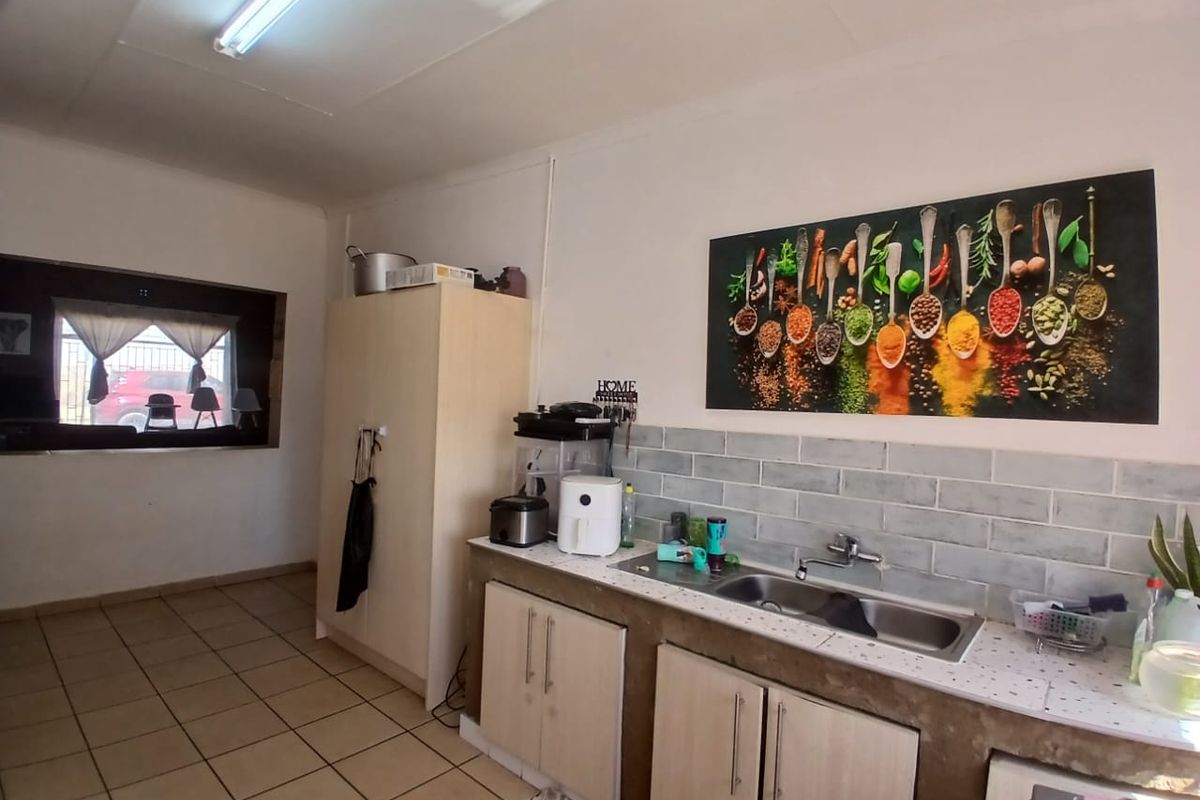 A functional kitchen featuring a double bowl sink, subway tile backsplash, and built-in cabinetry with ceramic floor tiles.