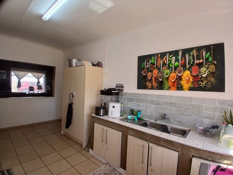 A functional kitchen featuring a double bowl sink, subway tile backsplash, and built-in cabinetry with ceramic floor tiles.