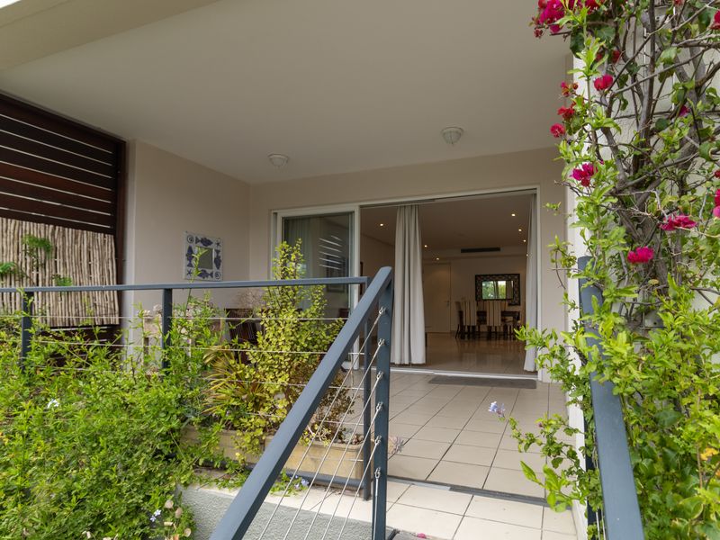 A covered patio area featuring tiled flooring, a modern metal railing, and a sliding glass door providing seamless access to the interior living space.