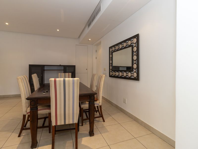 A well-maintained dining area featuring neutral tiled flooring, recessed ceiling lighting, and integrated ducted air conditioning.