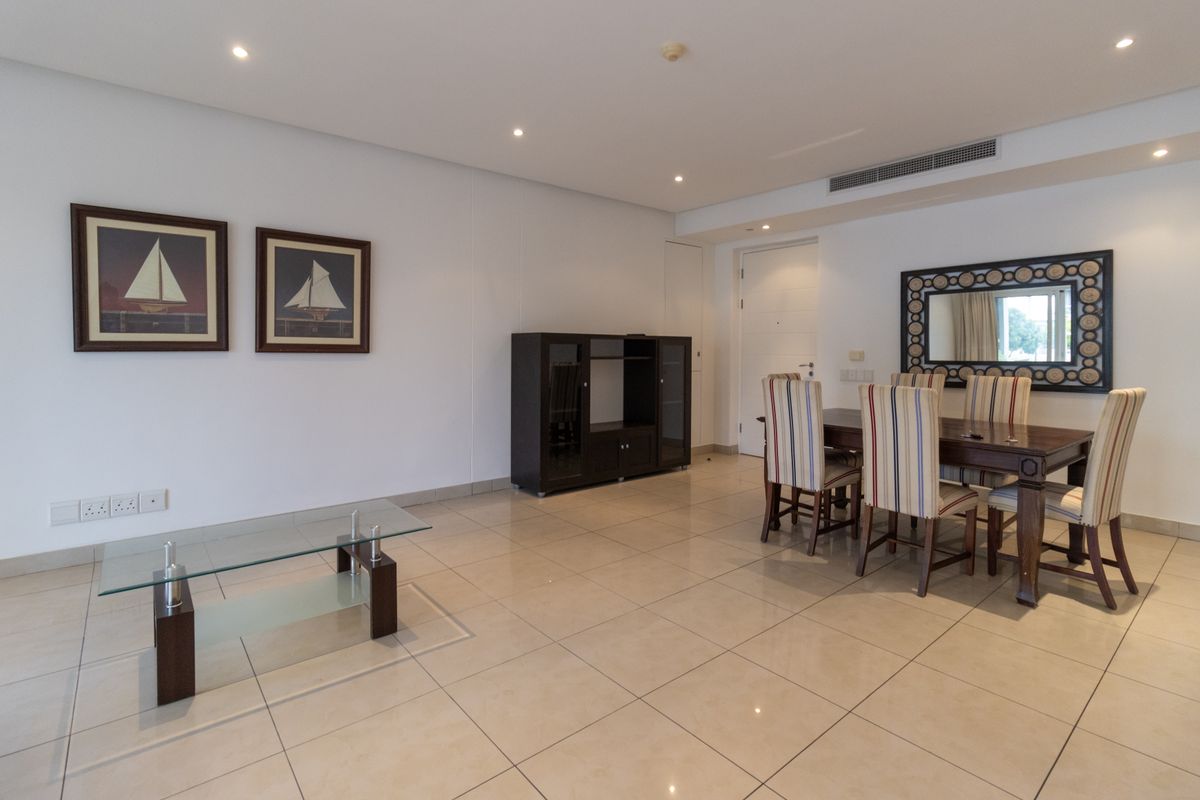A spacious living and dining area featuring neutral tiled flooring, recessed downlighting, and integrated ducted air conditioning.