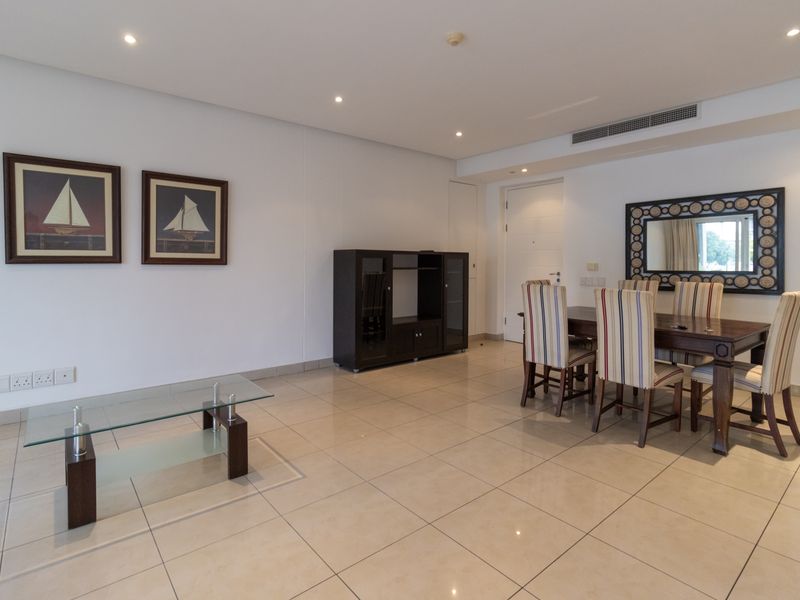 A spacious living and dining area featuring neutral tiled flooring, recessed downlighting, and integrated ducted air conditioning.