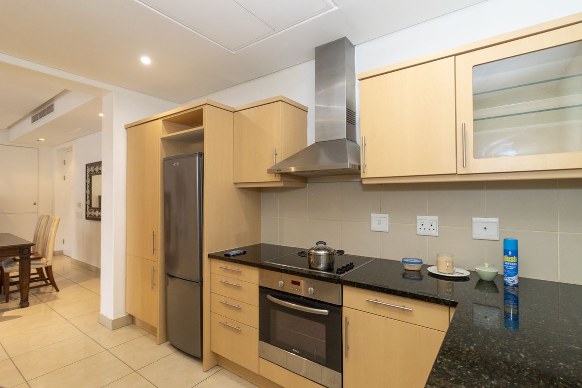 A functional kitchen featuring light wood cabinetry, granite countertops, stainless steel appliances, and tiled flooring, offering a clean and practical cooking space.