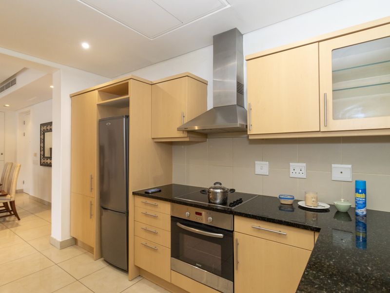 A functional kitchen featuring light wood cabinetry, granite countertops, stainless steel appliances, and tiled flooring, offering a clean and practical cooking space.