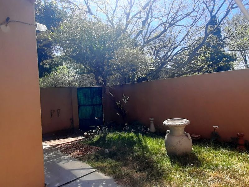 A private rear courtyard featuring a paved walkway, boundary walls, and a metal access gate, offering potential for landscaping and outdoor living improvements.