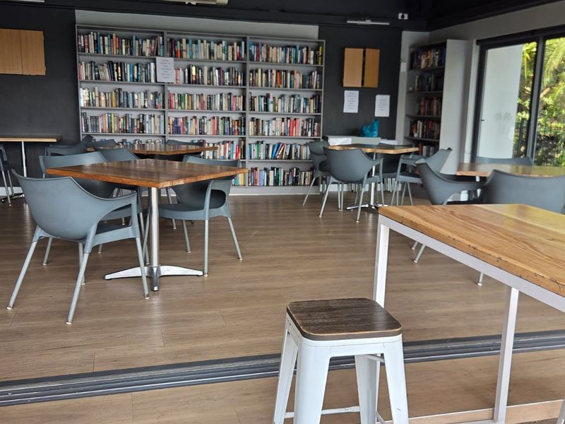 A communal living space featuring extensive built-in bookshelves, laminate flooring, and large sliding glass doors that open to an outdoor area.