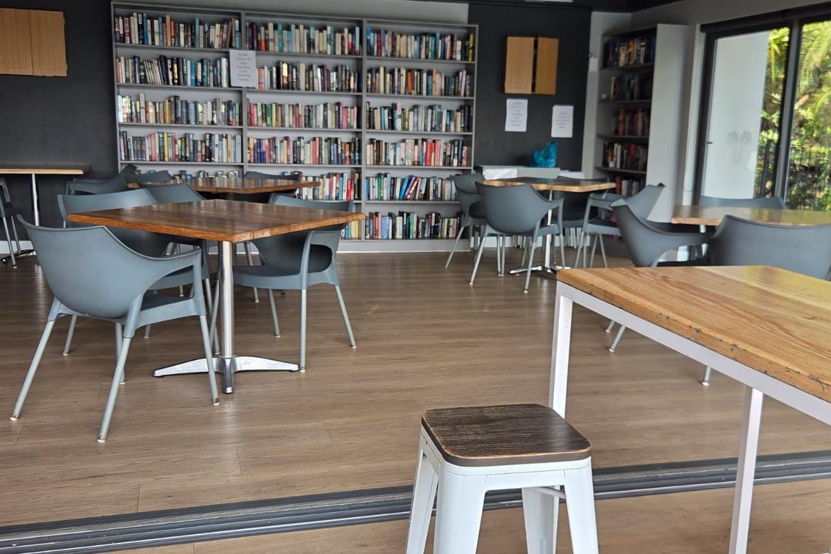 A communal living space featuring extensive built-in bookshelves, laminate flooring, and large sliding glass doors that open to an outdoor area.