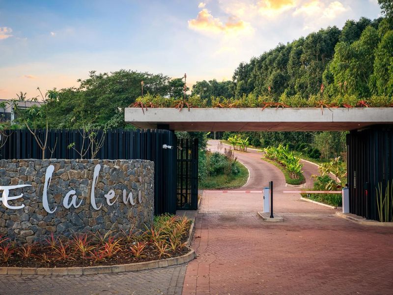 The entrance to Elaleni estate features a modern stone-clad wall, a secure boom gate, and a landscaped concrete canopy leading into the residential area.