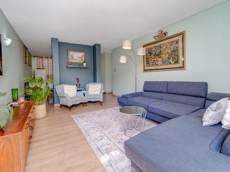 A well-maintained living room featuring light-toned laminate flooring and a distinct blue-painted feature wall with a built-in display niche.