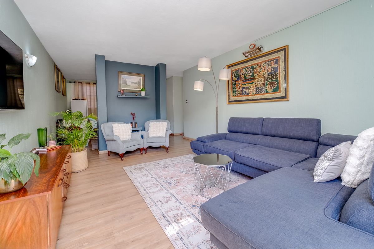 A well-maintained living room featuring light-toned laminate flooring and a distinct blue-painted feature wall with a built-in display niche.