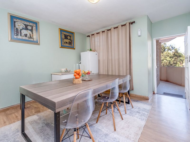 A dining area featuring light-toned laminate flooring and direct access to an outdoor balcony through a standard door.
