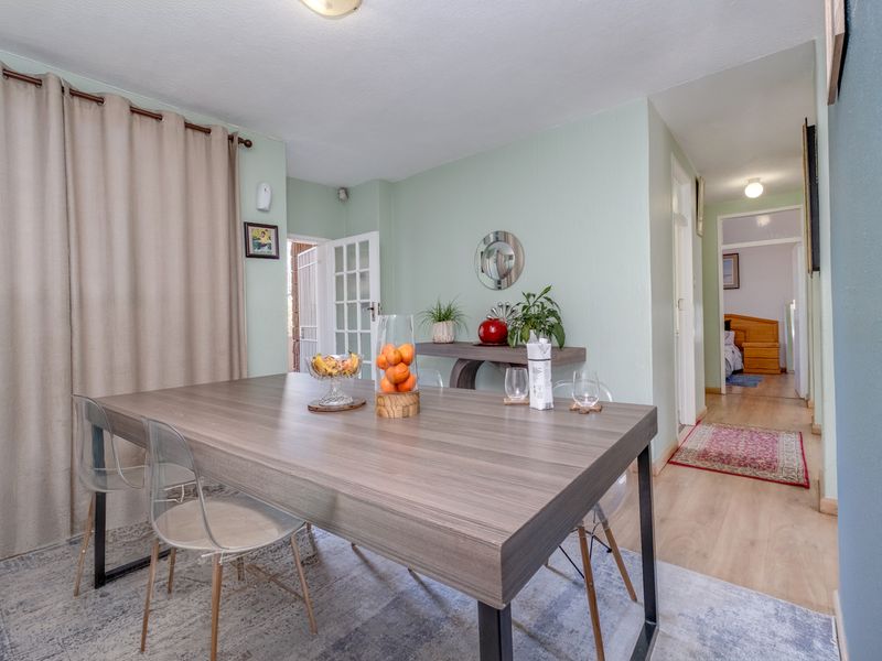 A bright dining area featuring laminate flooring, neutral walls, and a glass-paneled door leading to an outdoor space.