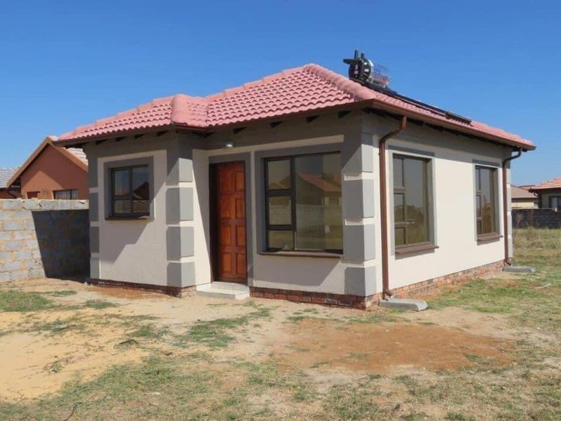 A modern single-story detached house featuring a tiled roof, solar water heater, and neutral exterior paint with contrasting corner detailing.
