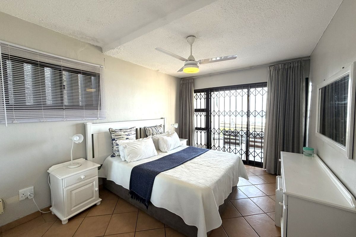 A bedroom featuring tiled flooring, a ceiling fan, and a sliding glass door with a security gate leading to an outdoor area.