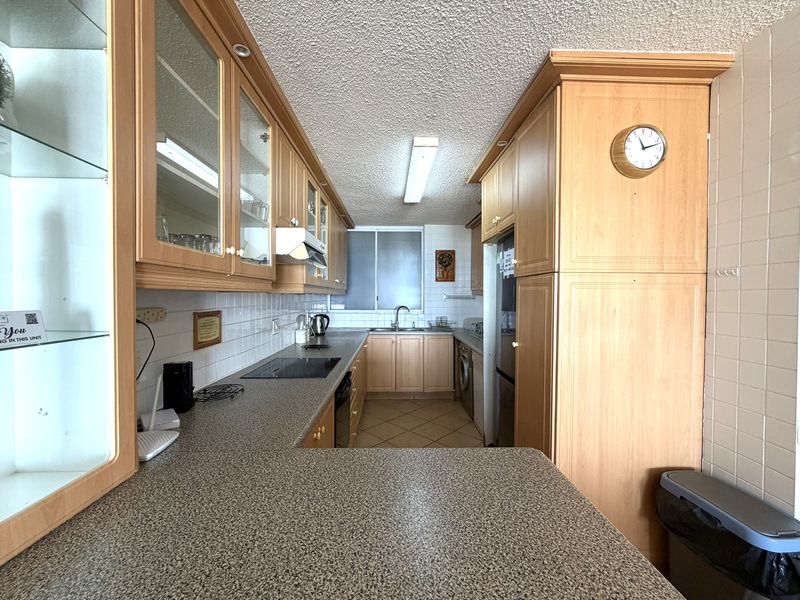 A functional kitchen featuring laminate cabinetry, granite-look countertops, ceramic tile backsplash, and integrated appliances, offering a practical layout for daily use.