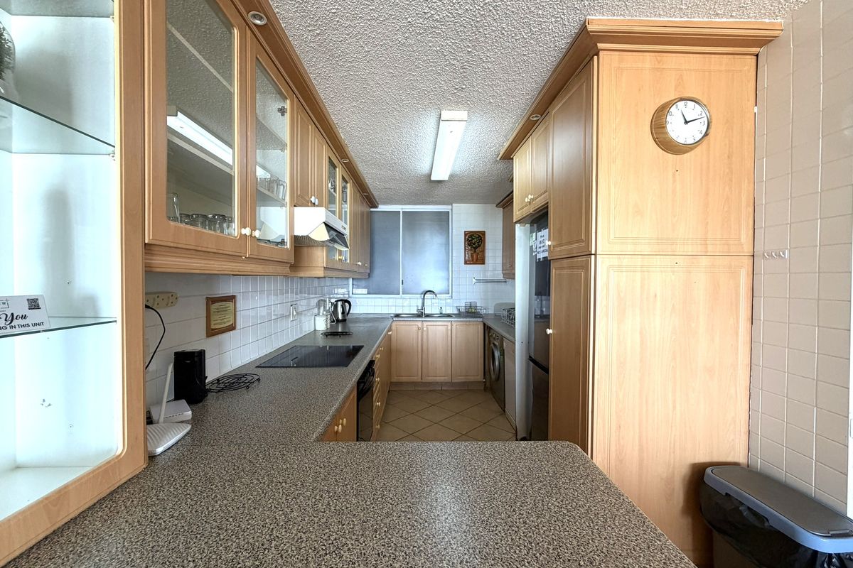 A functional kitchen featuring laminate cabinetry, granite-look countertops, ceramic tile backsplash, and integrated appliances, offering a practical layout for daily use.