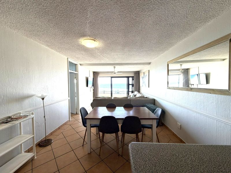 Open plan living and dining area featuring ceramic tile flooring, textured ceilings, and sliding glass doors leading to an outdoor view.