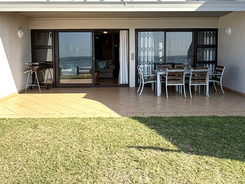 A covered patio area featuring tiled flooring, sliding glass doors with security gates, and direct access to a private garden space.