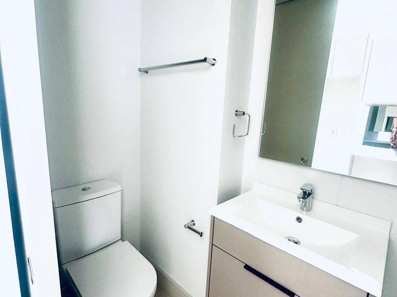 A clean, modern bathroom featuring a wall-mounted vanity with a ceramic basin, chrome fixtures, and a large mirror.