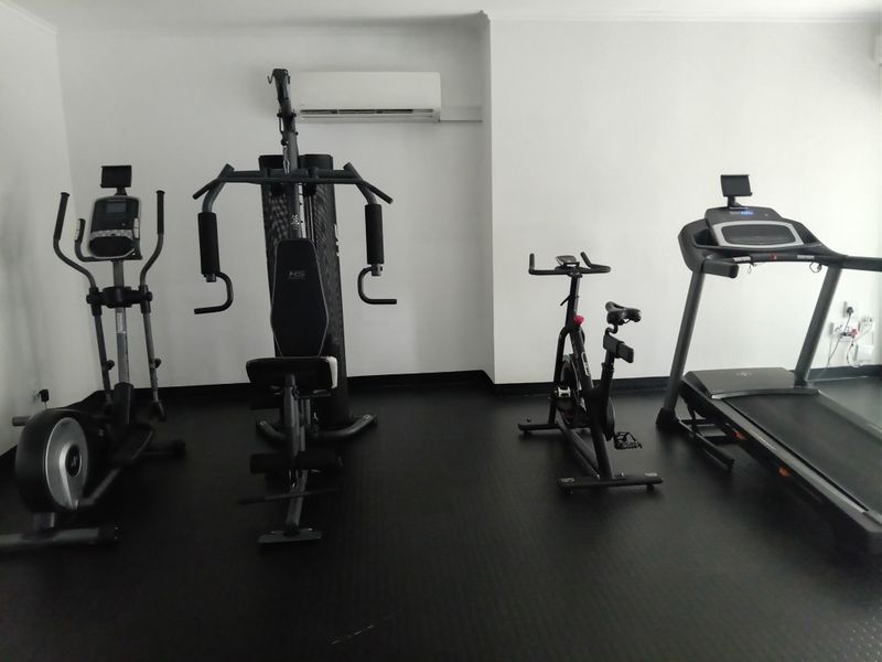 A dedicated home gym space featuring durable rubberized flooring and a wall-mounted split-system air conditioning unit for climate control.