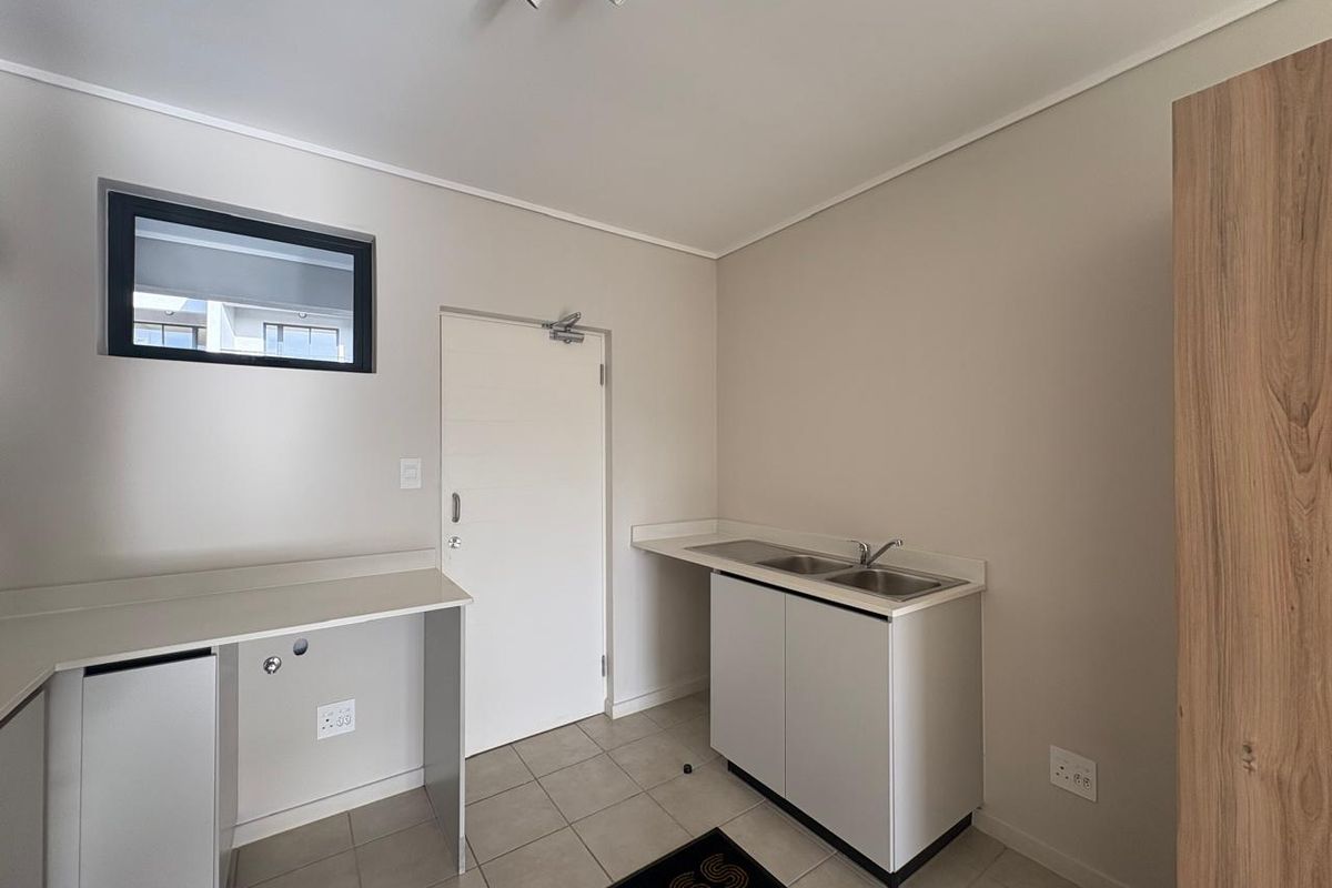 A clean and functional laundry room featuring tiled flooring, built-in cabinetry with a double sink, and dedicated plumbing connections for appliances.